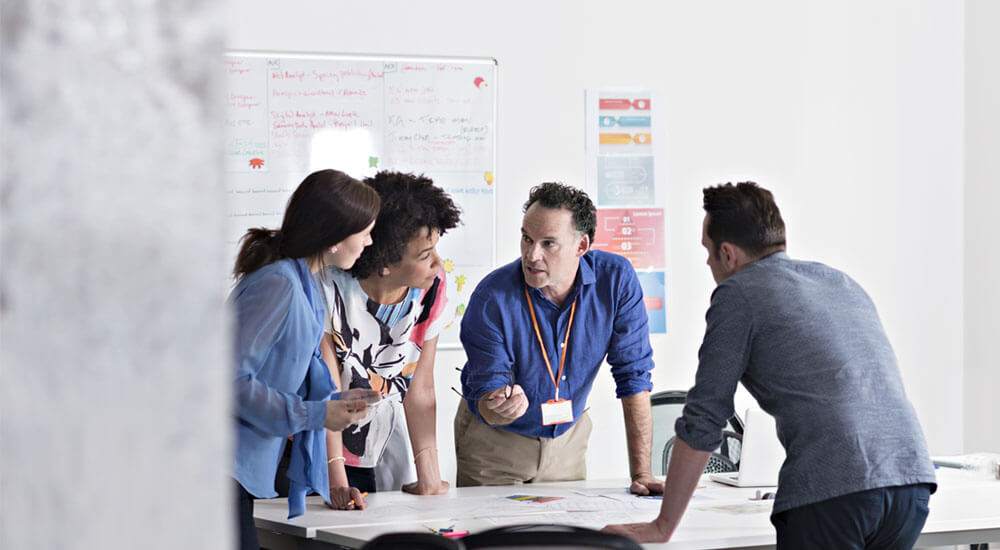 Group of colleagues standing and discussing an issue in the workplace